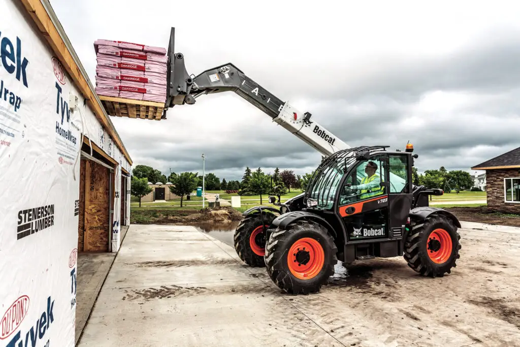 Bobcat telehander loads a pallet of roof shingles on a new home build