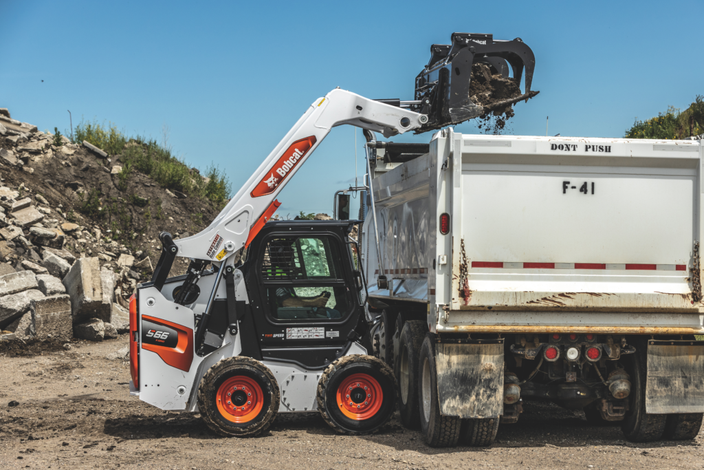 Bobcat loading broken concrete into a dump truck